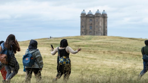 Visitors walking in the parkland with view of the Birdcage in the distance at Lyme Park